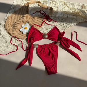Detailed view of red bikini with golden shell accents on textured swim fabric