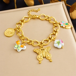 Detailed shot of gold plated bracelet featuring ceramic floral and butterfly pendants
