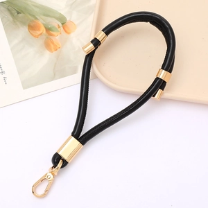 Detail of black PU leather wrist strap with gold metal lobster clasp and reinforced ring
