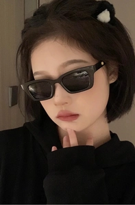 Detail of vintage black narrow rectangular sunglasses with gold circular metal hinge accents
