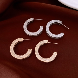 Detail showing gold and silver C-shaped hoop earrings with micro-pave crystals on silk