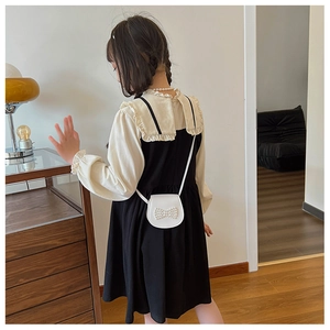 Rear view of a girls black and white long sleeve dress with pearl bow mini bag