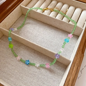 Detail of green beaded floral necklace displayed in a textured wooden jewelry box