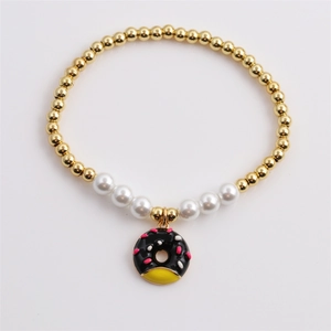 Women gold bead and white pearl bracelet featuring a colorful enamel donut charm