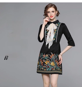 Detail of high-density floral embroidery on a black dress with bow tie collar