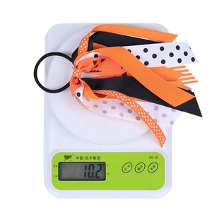 Halloween ribbon hair scrunchie with pumpkin patterns shown weighing 10.2g on a scale