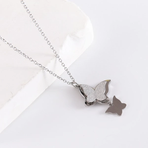 Double-layered stainless steel butterfly pendant necklace on a white textured stone