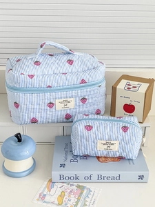 Detailed close-up of blue striped quilted makeup bag set with cute strawberry prints