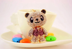 Close-up of a panda keychain with gold metal plating and sparkling pink rhinestones