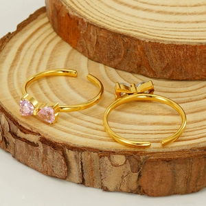 Set di anelli dorati con fiocco in zircone rosa e trasparente su base di legno
