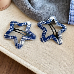 Detail of star-shaped hair clips with blue plaid fabric finish and black BB clip structure