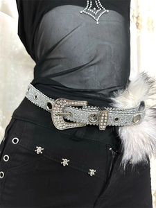 Détail d'une ceinture argentée à strass avec boucle et charm en fausse fourrure grise