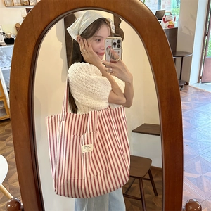 Detail of red and white striped canvas tote bag with front pocket and text patch