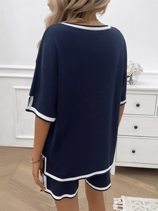 Rear view of dark blue two-piece lounge set with white stripes on a model in a bedroom