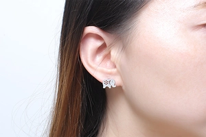 Detail of silver elephant stud earring with hollow flower design and white crystal eye