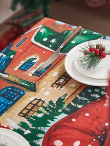 Detailed close-up of woven Christmas tablecloth with festive snowy village and pine trees