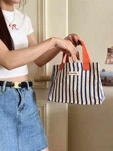 Blue and white striped tote bag with orange handles and seersucker textured fabric