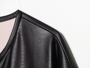 Detailed close-up of fine stitching and black leather texture on shoulder and collar