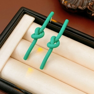 Detail of green knot stud earrings with a matte finish displayed in a jewelry gift box