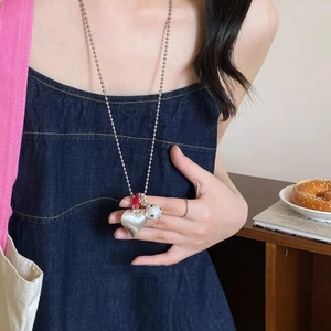 Silver heart and spotted ball pendant necklace worn on denim for a chic aesthetic