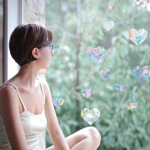 Rainbow prism heart window film showing holographic effects on glass with a woman background