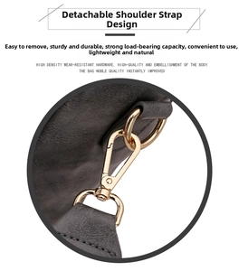 Detail of detachable gold hook hardware and stitched textured leather strap on dark grey bag