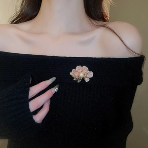 Detail of pink enamel flower brooch with pearl and crystals on black knitwear