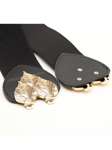 Detail of leaf-shaped gold metal buckle on a black elastic waist belt for women
