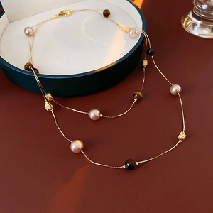 Detail of layered pearl necklace with tiger eye stones and golden beads on a jewelry tray