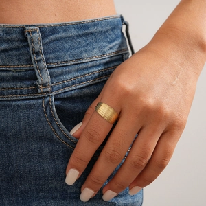 Macro shot of a layered gold-plated wide band ring on a woman's hand with denim background