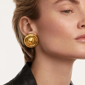 Close-up of oversized gold textured round stud earring worn on model for a bold style