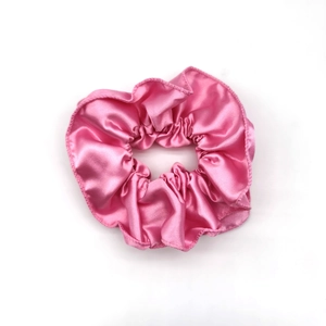 Detailed close-up showing the smooth pink satin texture and pleats of the elastic scrunchie