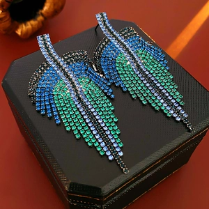 Macro shot of leaf-shaped earrings with blue-green gradient rhinestones on jewelry box