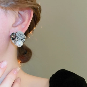 Gros plan d'une boucle d'oreille rose argentée avec perle blanche et pierre grise