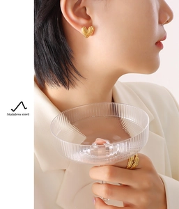 Detail of elegant gold heart earring and feather ring set in polished stainless steel