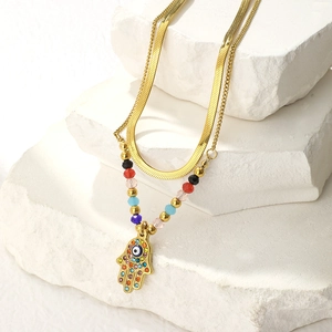 Gold double-layer necklace with Hamsa Hand and Evil Eye pendant on white stone