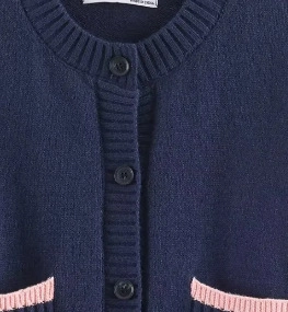 Vue détaillée du cardigan bleu marine avec bordure rose contrastée et boutons noirs