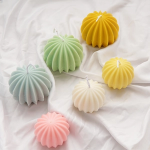 Colorful ball-shaped cactus scented candles on white silk background top view