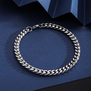 Polished silver stainless steel Cuban chain bracelet on a textured blue background