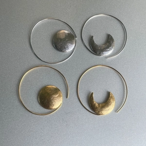Macro detail of hammered gold and silver sun and moon asymmetric hoop earrings