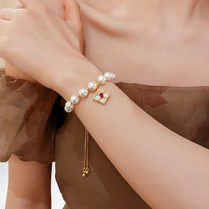 Detailed shot of a gold-plated pearl bracelet with a clover pendant and adjustable chain