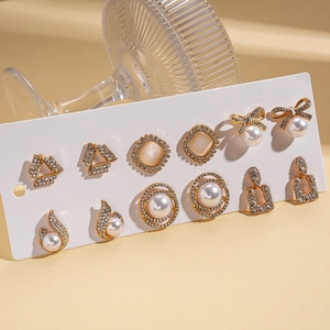 12-piece elegant gold earring set with rhinestones, pearls and bow designs on display