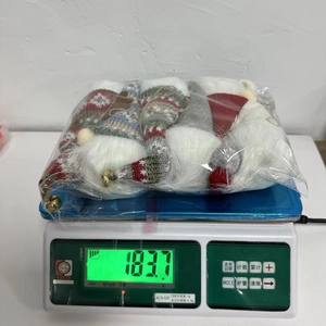 Three plush Christmas gnomes in festive colors on a scale showing 183.7g weight