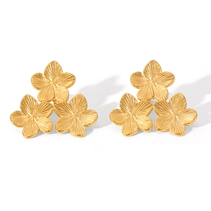 Détail macro de boucles d'oreilles dorées à trois fleurs avec texture métallique fine