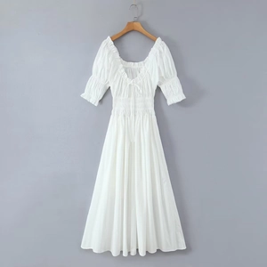 Détail de la taille smockée et du col carré à volants sur robe blanche à manches bouffantes