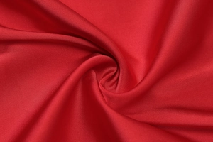 Detailed macro view of the luxurious red satin mesh fabric texture with elegant folds