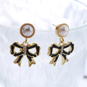 Détail de boucles d'oreilles papillon dorées avec émail noir et perles sur verre