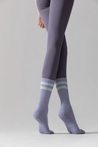Detail of purple yoga socks with green stripes and non-slip silicone grips on sole