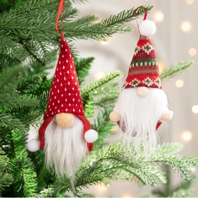 Macro detail of knitted Christmas gnome ornaments hanging on a pine tree with warm bokeh light