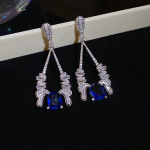 Macro shot of cushion-cut blue sapphire earrings with glittering pave zircon accents